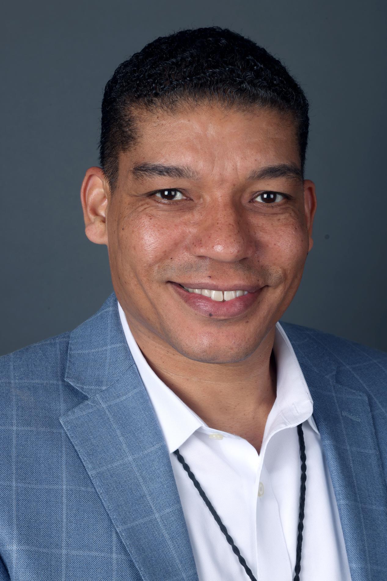 Headshot of an African American man, facing forward, in white shirt and blue suit jacket